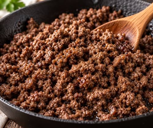 Browned seasoned 93/7 ground beef in a cast iron skillet with a wooden spoon